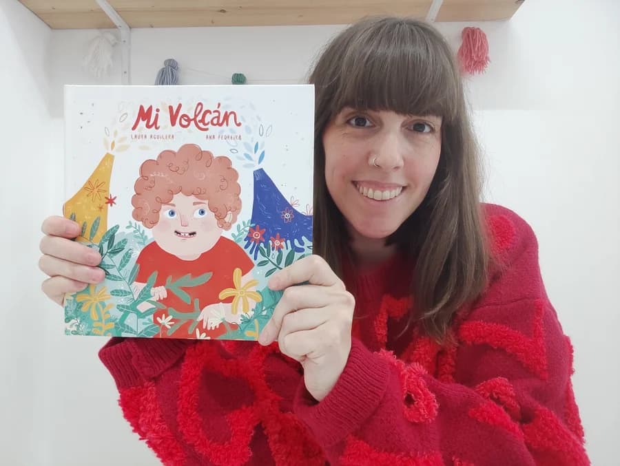 Laura Aguilera sosteniendo el cuento Mi volcán en su consulta